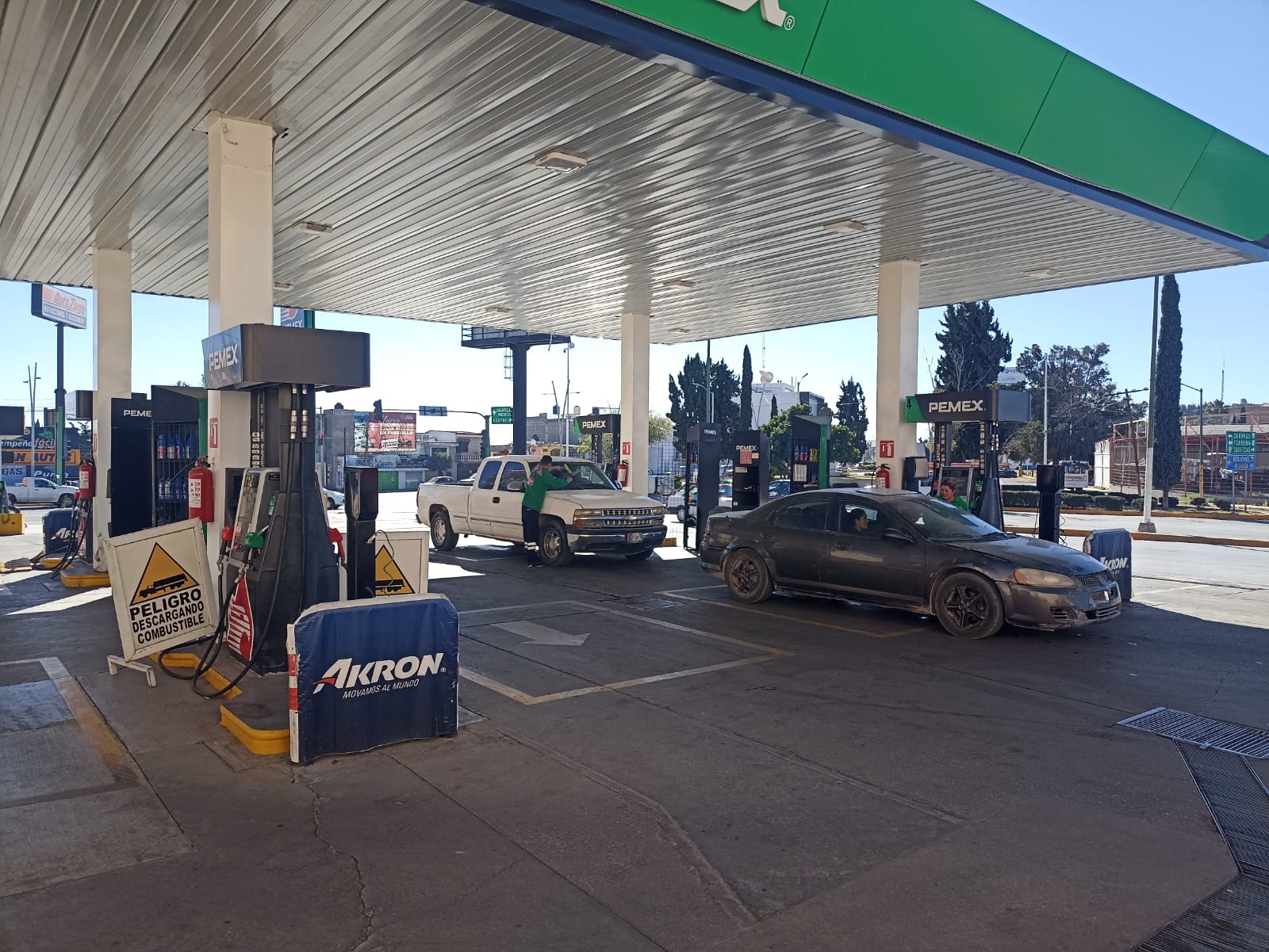 una estación de gasolina por la noche con coches estacionados en la bomba de gas