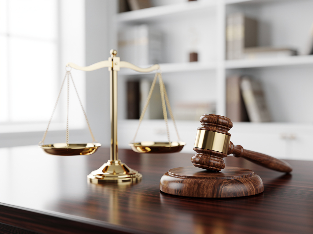 Mazo de juez y balanza de justicia sobre escritorio de madera en despacho legal