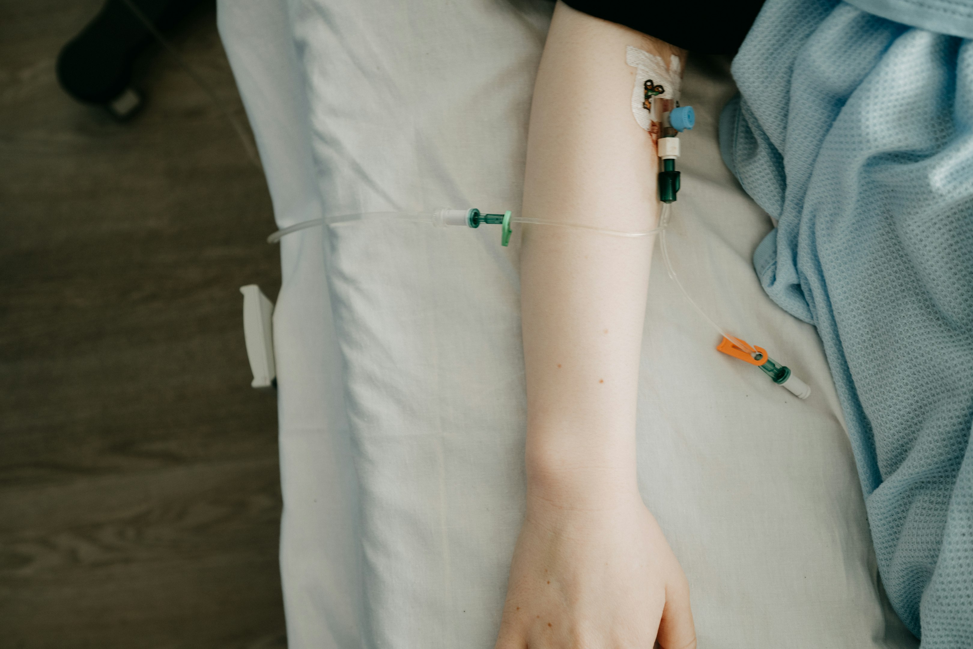 una persona acostada en una cama de hospital con un suero conectado a su brazo