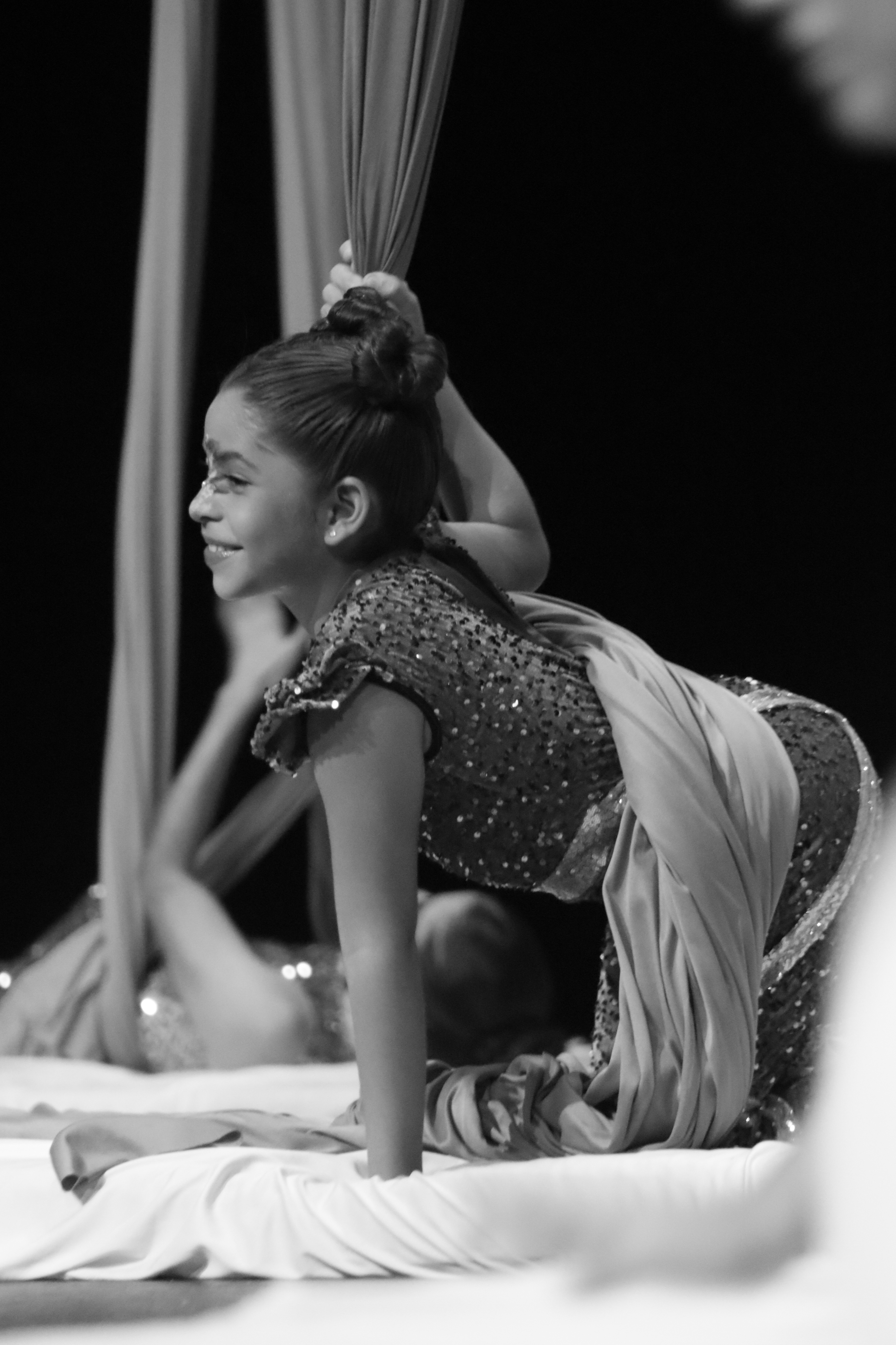 Un grupo de cuatro niñas sonrientes con ropa de deporte, en un espacio interior con un cartel de fondo.