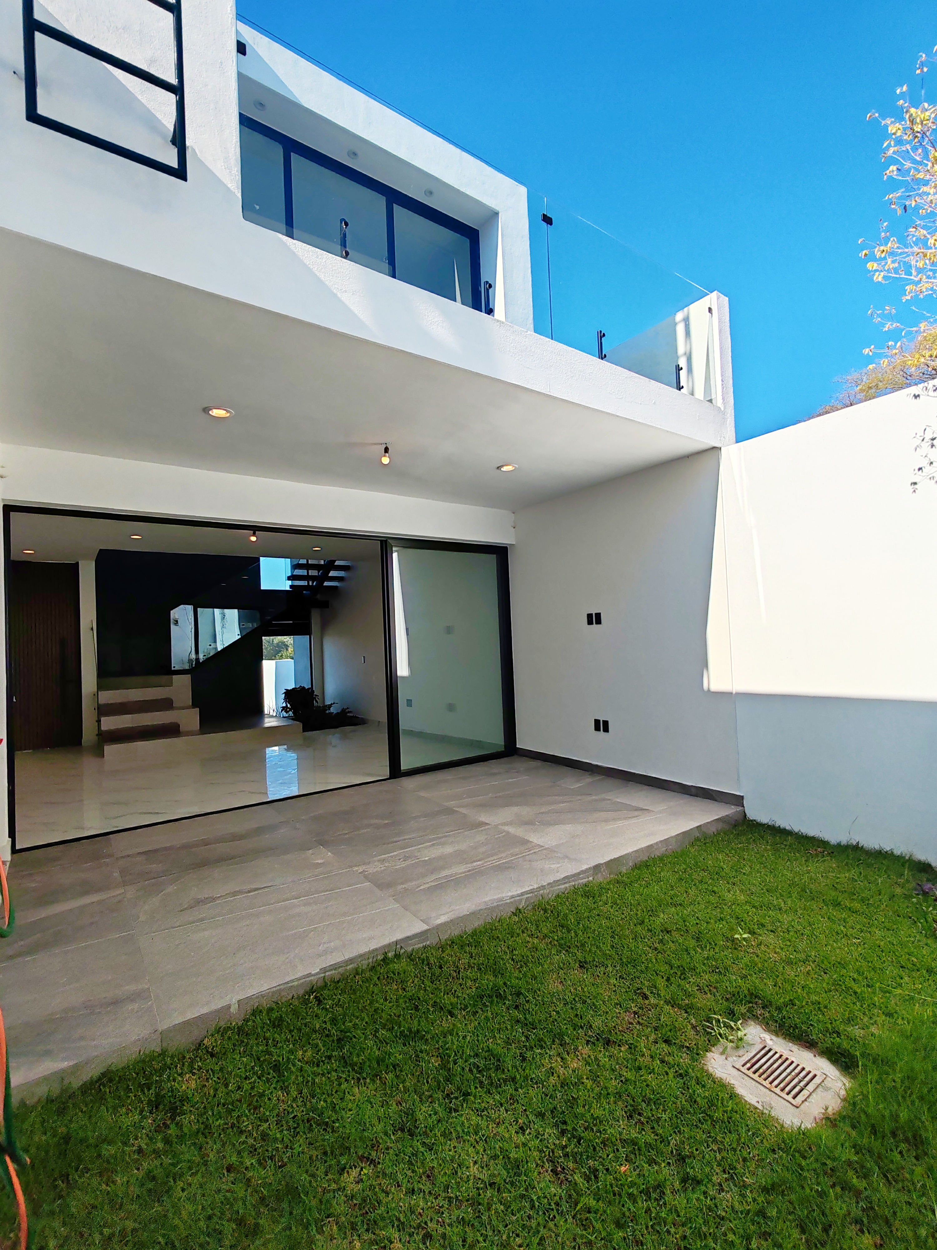 Casa de ladrillo de estilo victoriano con techos rojos y detallados adornos blancos, situada frente a una carretera.