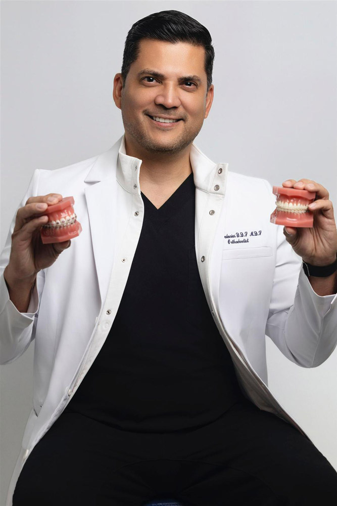 Doctor Palacios holding examples of metal and clear braces