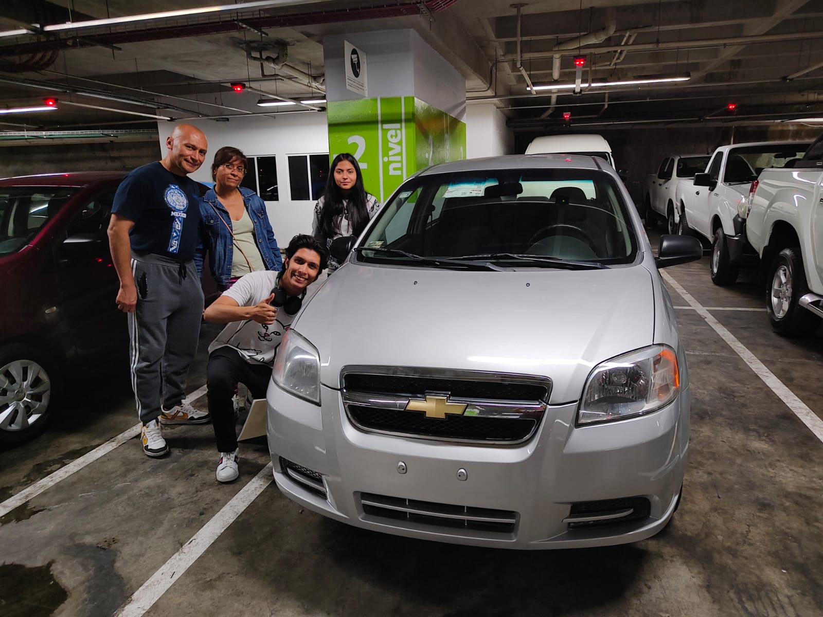 Person standing beside a white Nissan pickup truck in a dimly lit underground parking garage.