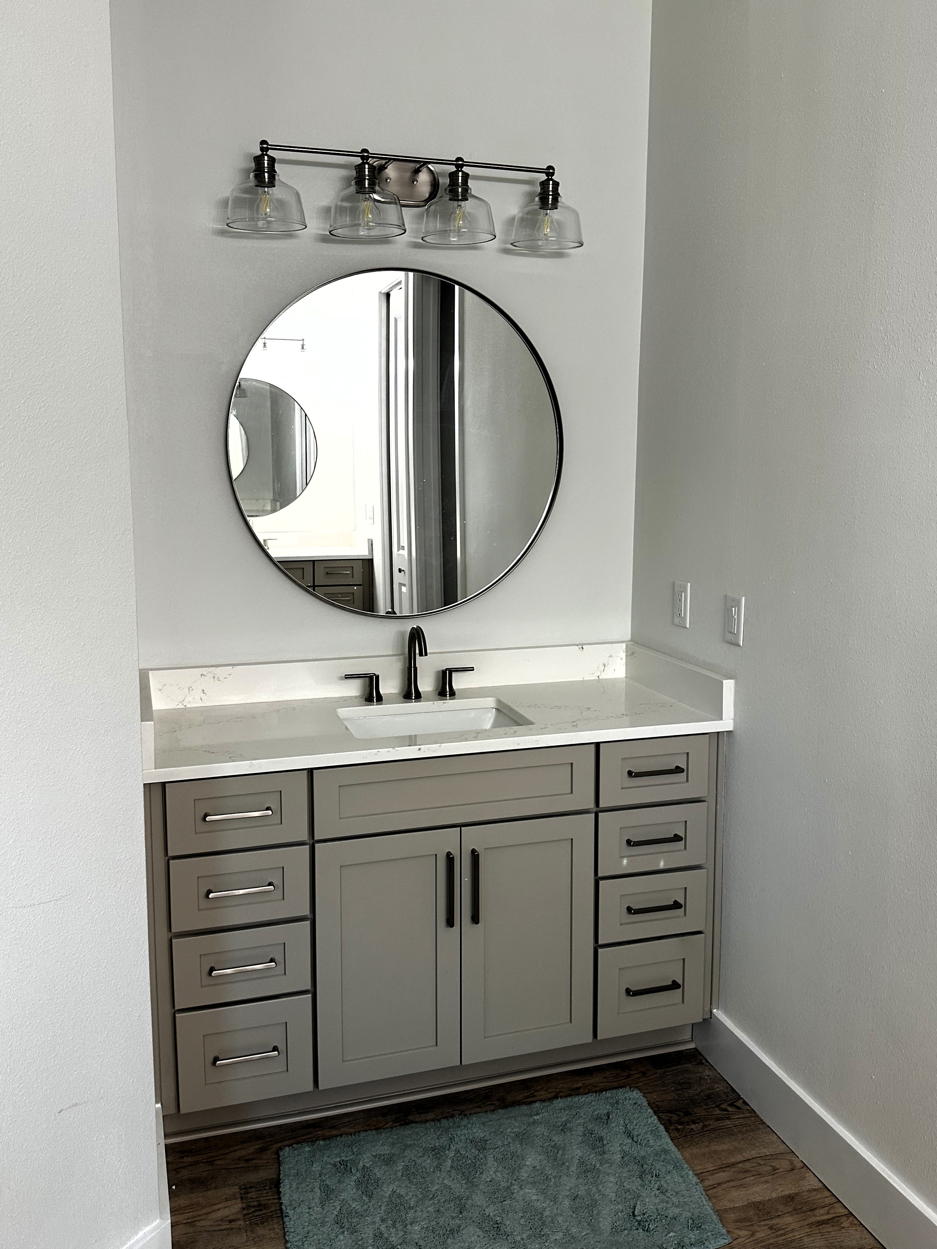 Semi-Custom painted vanity with beautifully framed mirror and lighting featuring Quartz countertops and matching 4" backsplash.