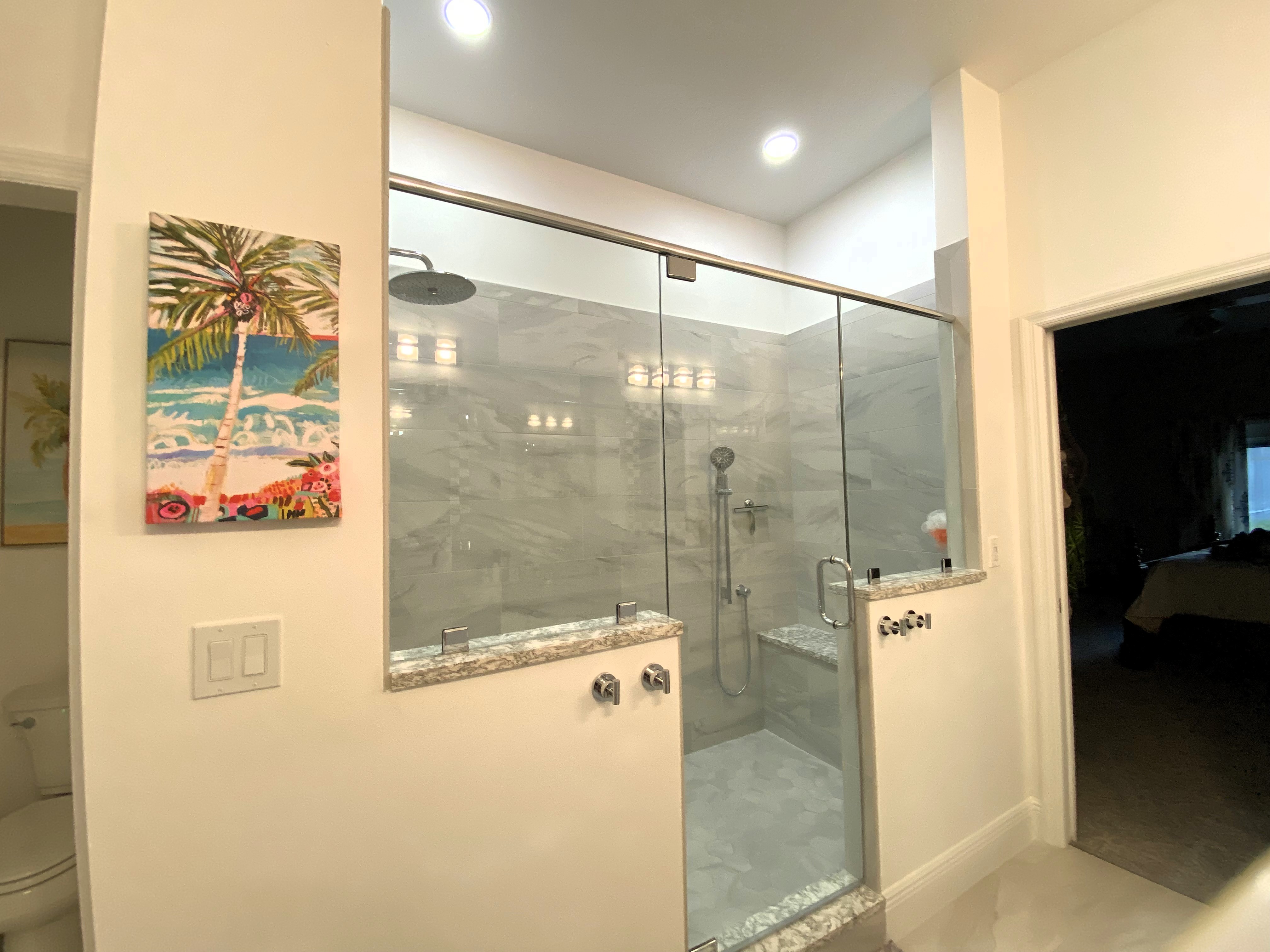 Perfectly framed walking in shower with bench featuring 3/8" heavy clear glass panels and door.
