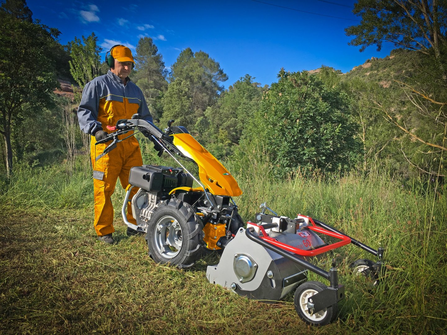 Tractor verde en campo de trigo con remolque, árboles al fondo.