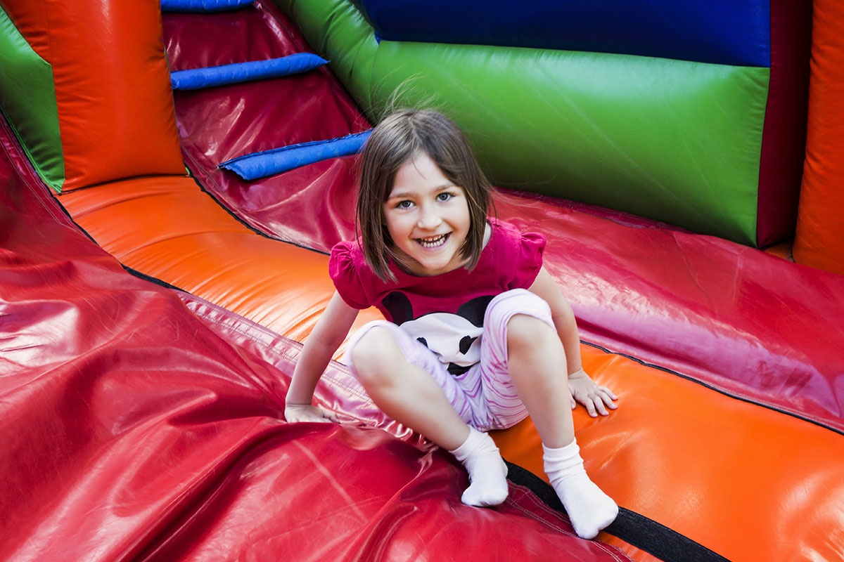 Girl Having Lots Of Fun On A Jumping Castle While Sliding