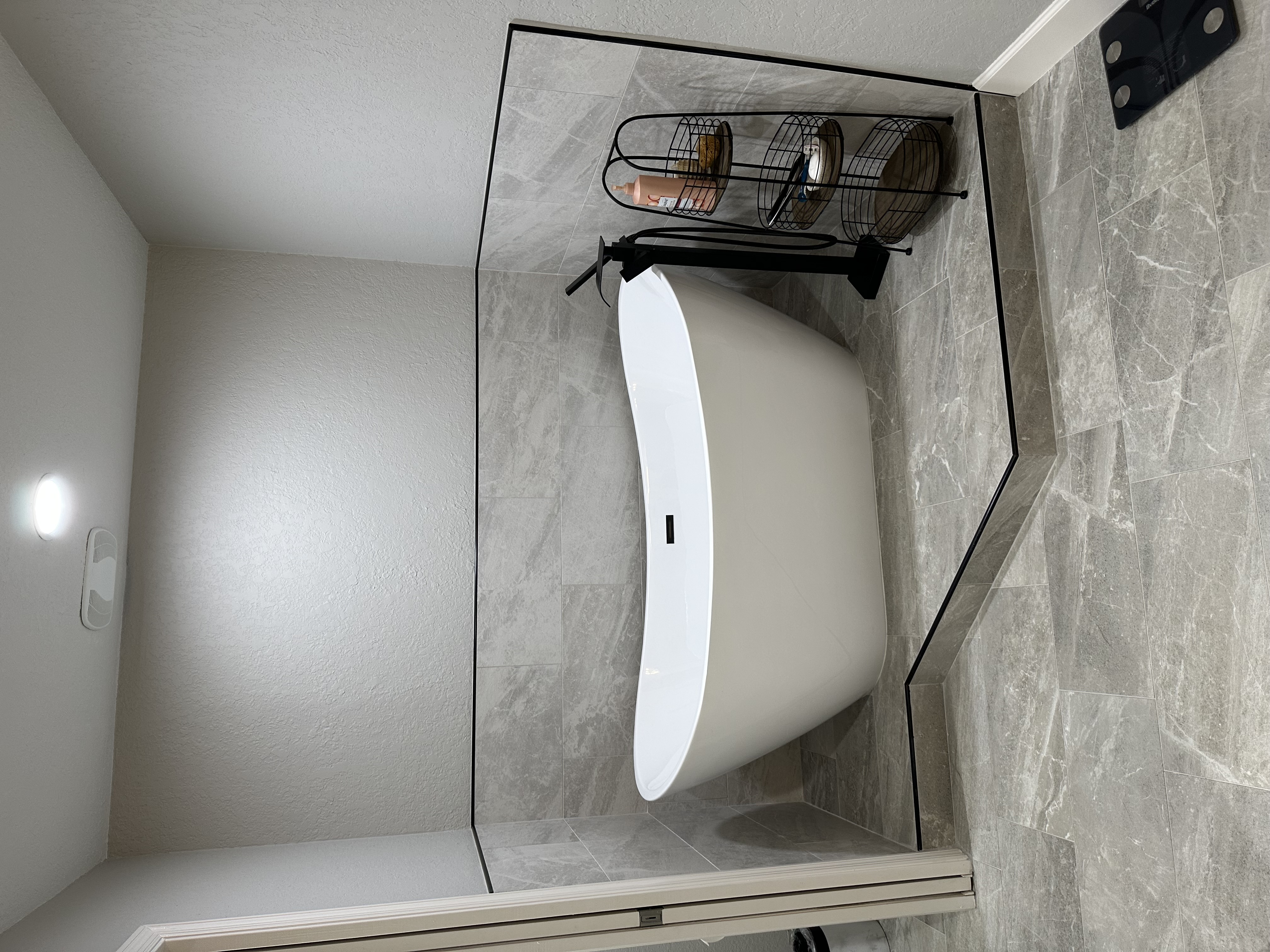 This freestanding soaking tub, complemented by matte black fixtures, makes for the perfect relaxing retreat, blending modern style with comfort.