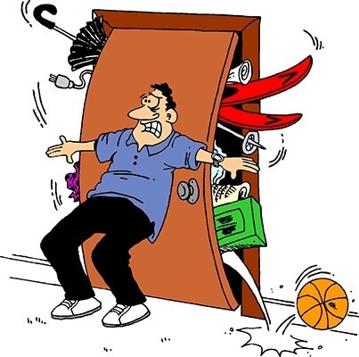 man holding items in a bulging closet in front of door man holding items in a bulging closet in front of door