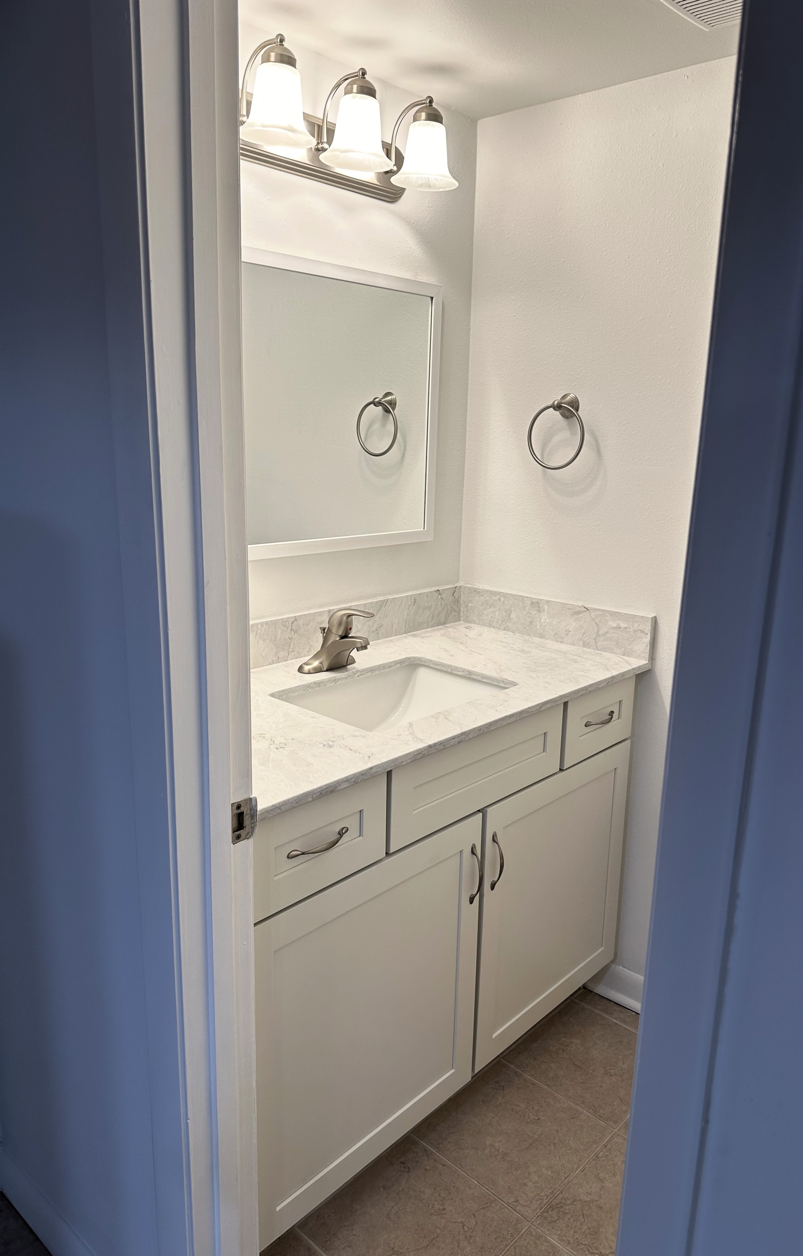 Perfect vanity featuring maple wood painted steam semi-custom cabinetry, quartz countertops with matching 4" backsplash, and satin nickel handles.