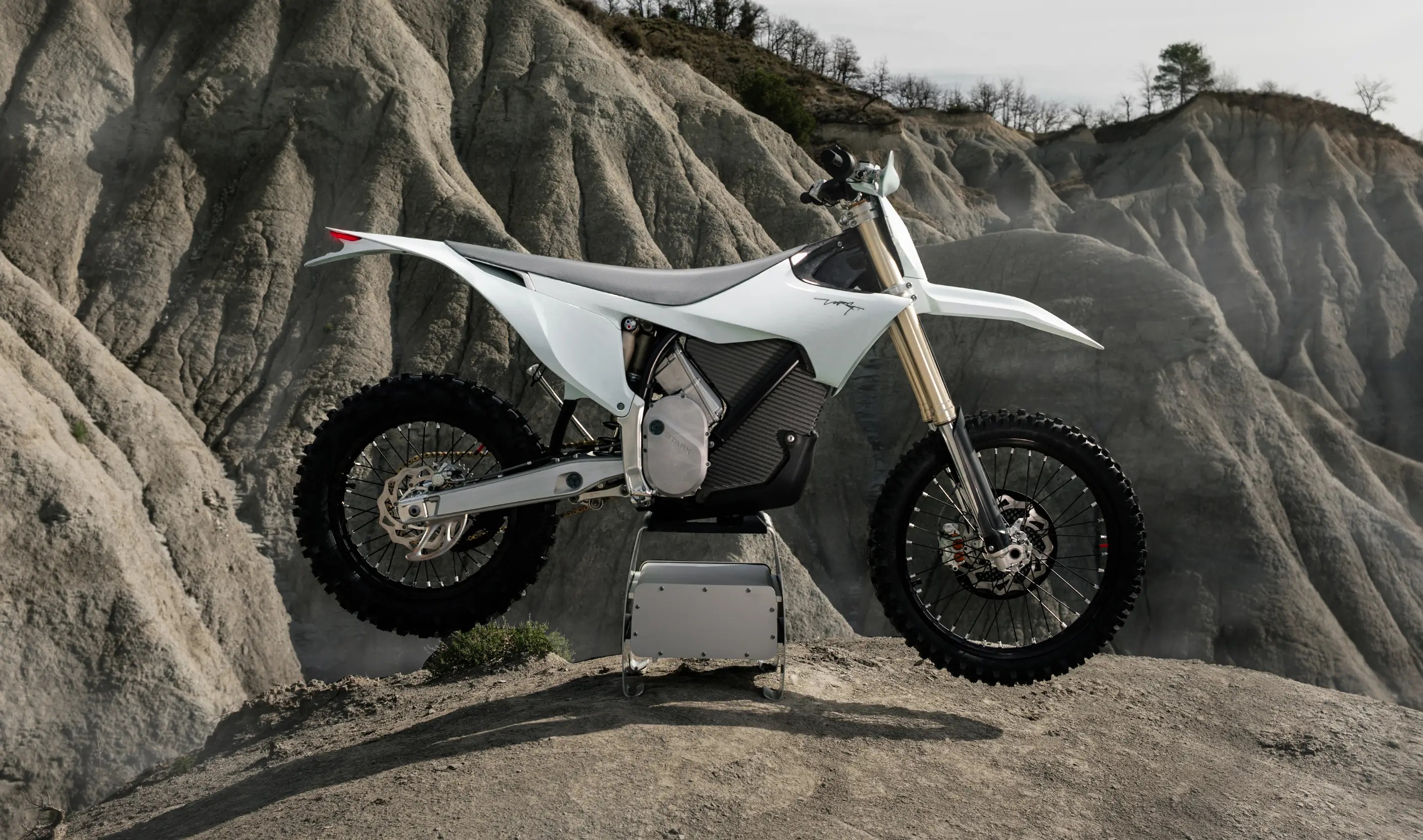 Motocicleta eléctrica de enduro blanca en terreno rocoso montañoso
