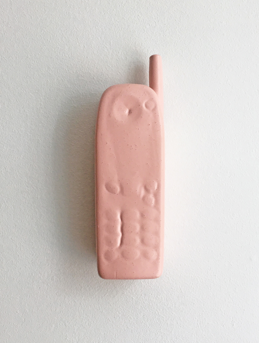 A vintage cellphone with antenna covered in a thick layer of poured pink paint.