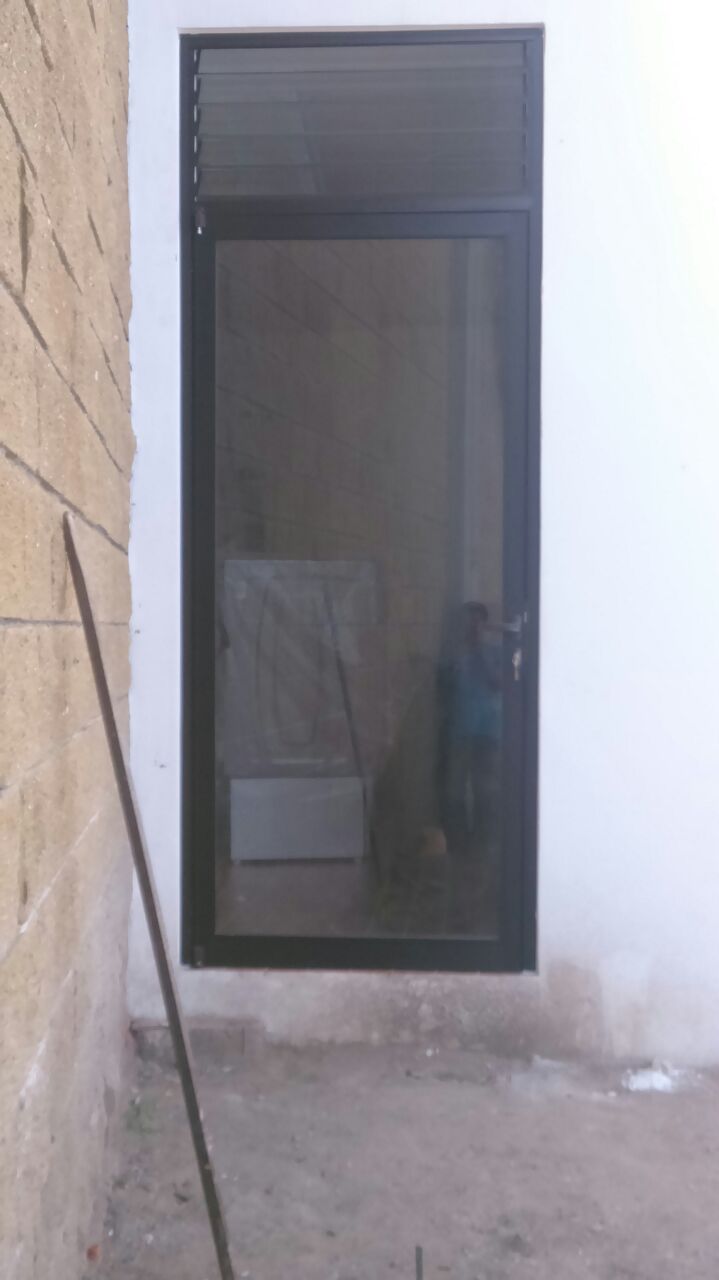 Puerta de aluminio tono bronce, con cristal filtrasol de 6mm, en la parte superior perciana.