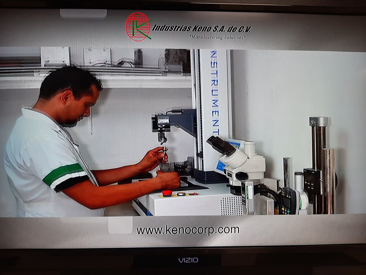 Hombre trabajando en un laboratorio con equipo de precisión y microscopio, logo de Industrias Keno S.A. de C.V. visible en la parte superior.