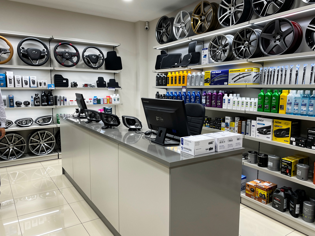 Tienda de accesorios para autos con llantas, volantes, aceites y repuestos exhibidos en estanterías
