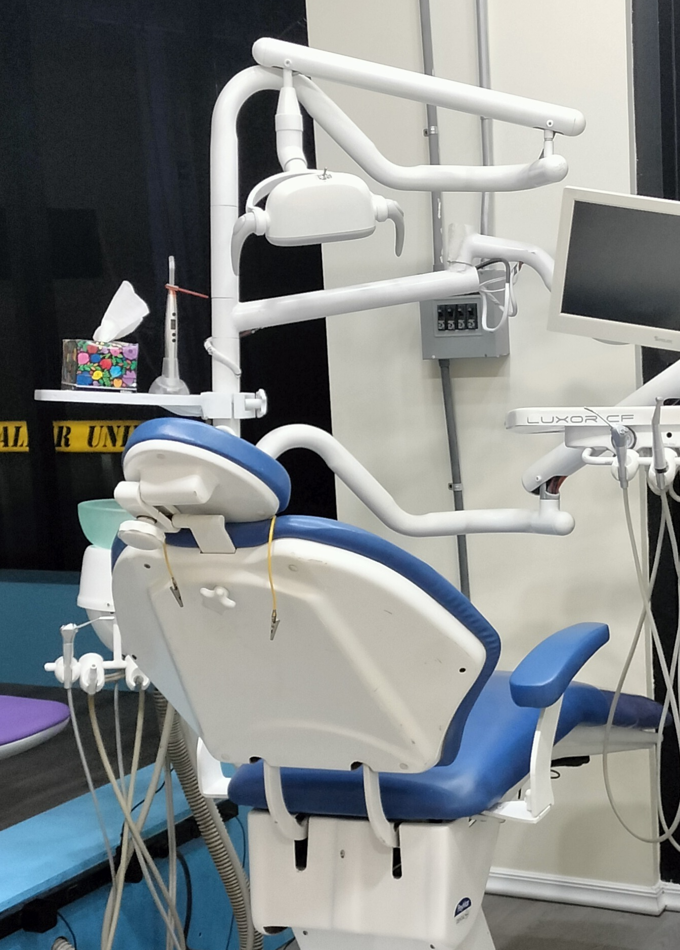 Sala de consulta dental moderna con silla odontológica, equipo de dentista y decoración en tonos azules.