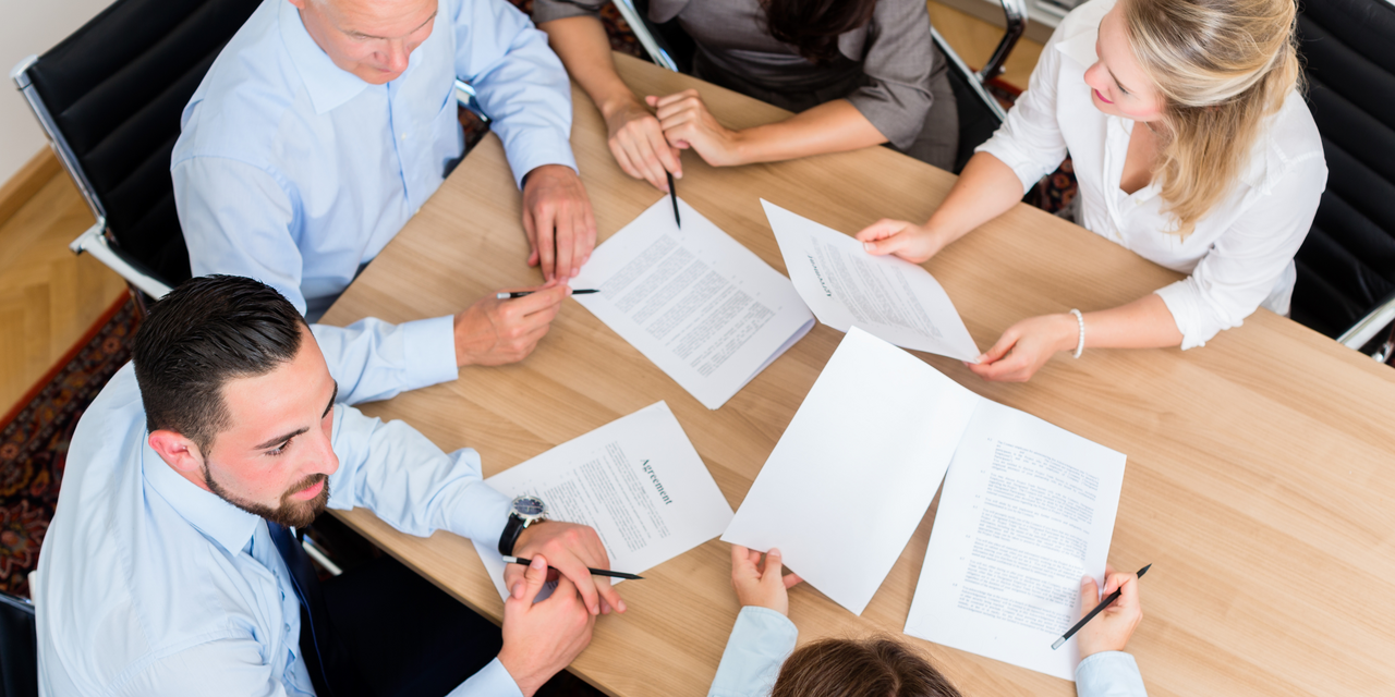 Business professionals in suits having a meeting at a glass table in a modern office
