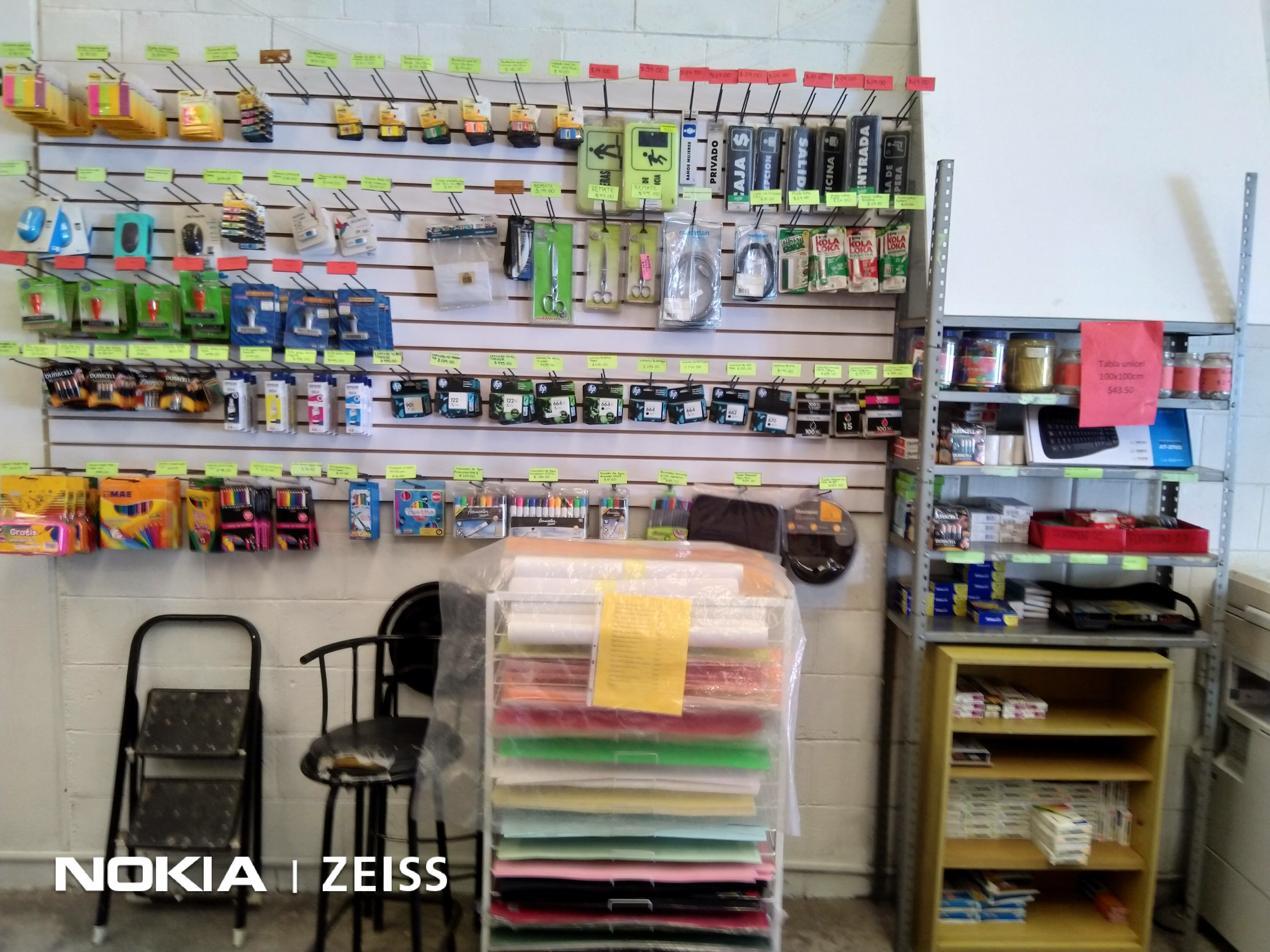 Estantería de papelería con artículos de oficina, como lápices, tijeras y papel, en una tienda.