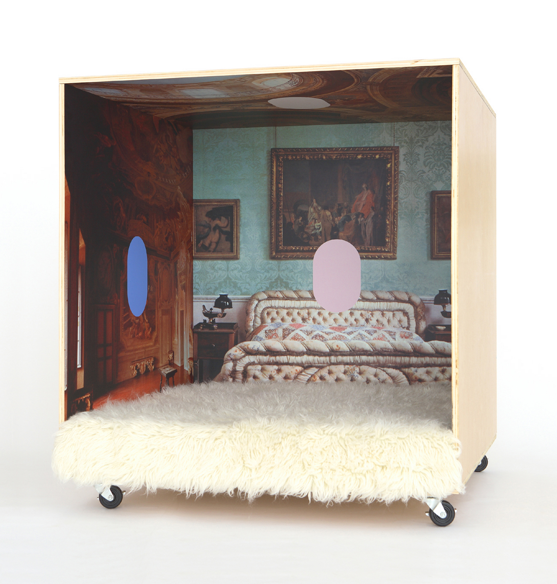 A plywood cube on wheels with an opulent interior with colorful oval graphics.