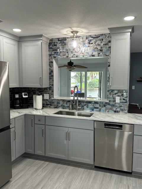 Chic kitchen featuring maple painted Owl Grey semi-custom cabinetry showcasing Dekton Trance countertop and Casale Shell Blue backsplash.