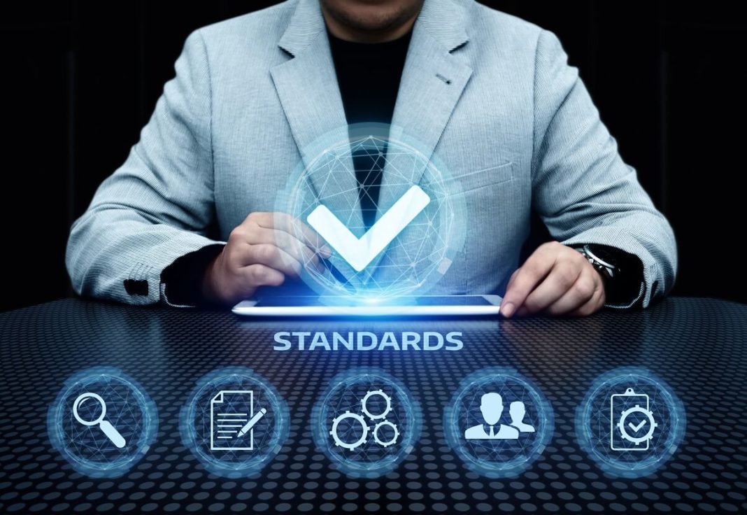 Primer plano de una mano con guante montando engranajes sobre una mesa de trabajo, en un entorno industrial.