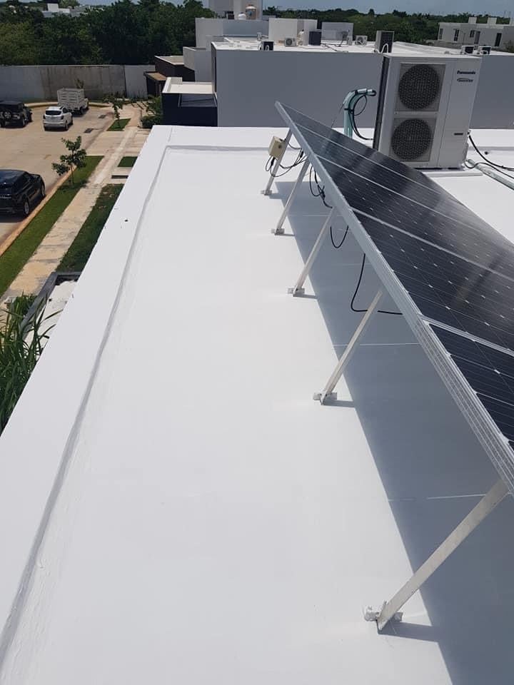 Paneles solares instalados en el techo de un edificio con unidades de aire acondicionado y vista a la urbanización.