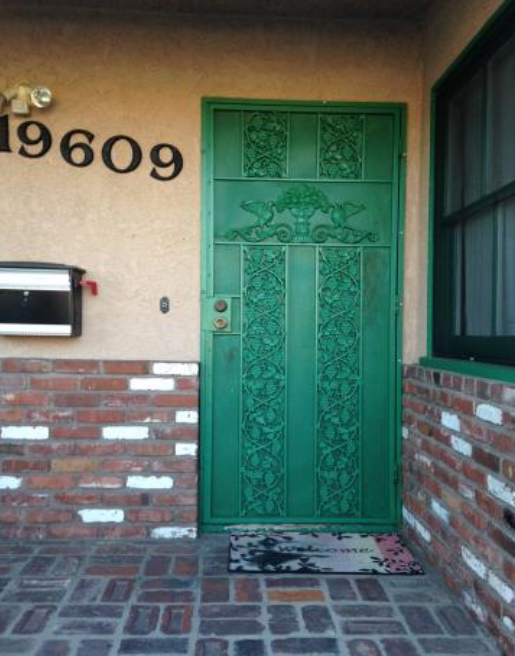 Green wrought iron door guard with decorative overlays.