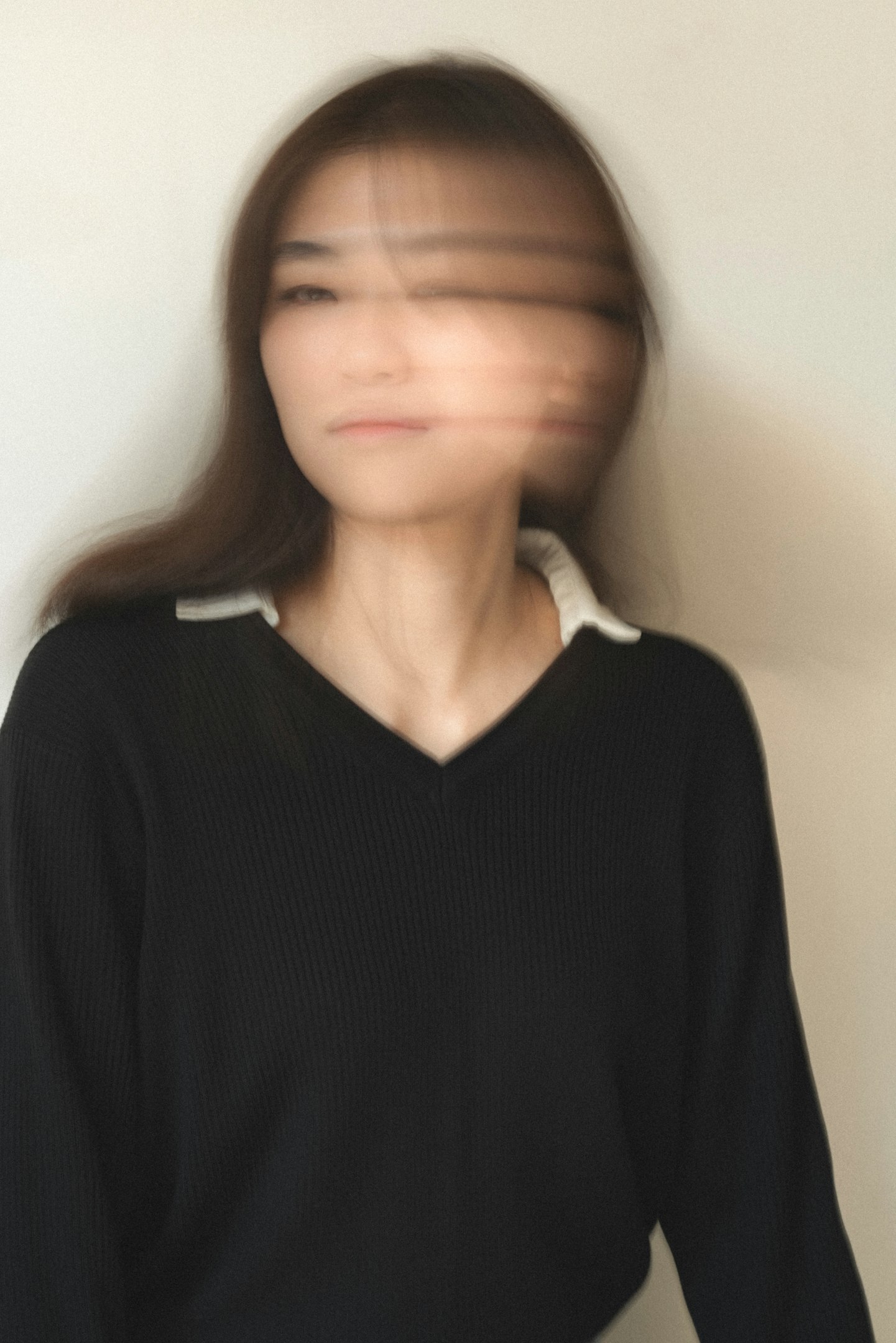 Smiling man in casual denim shirt working on a laptop at a bright, modern office desk with plants and shelves in the background.
