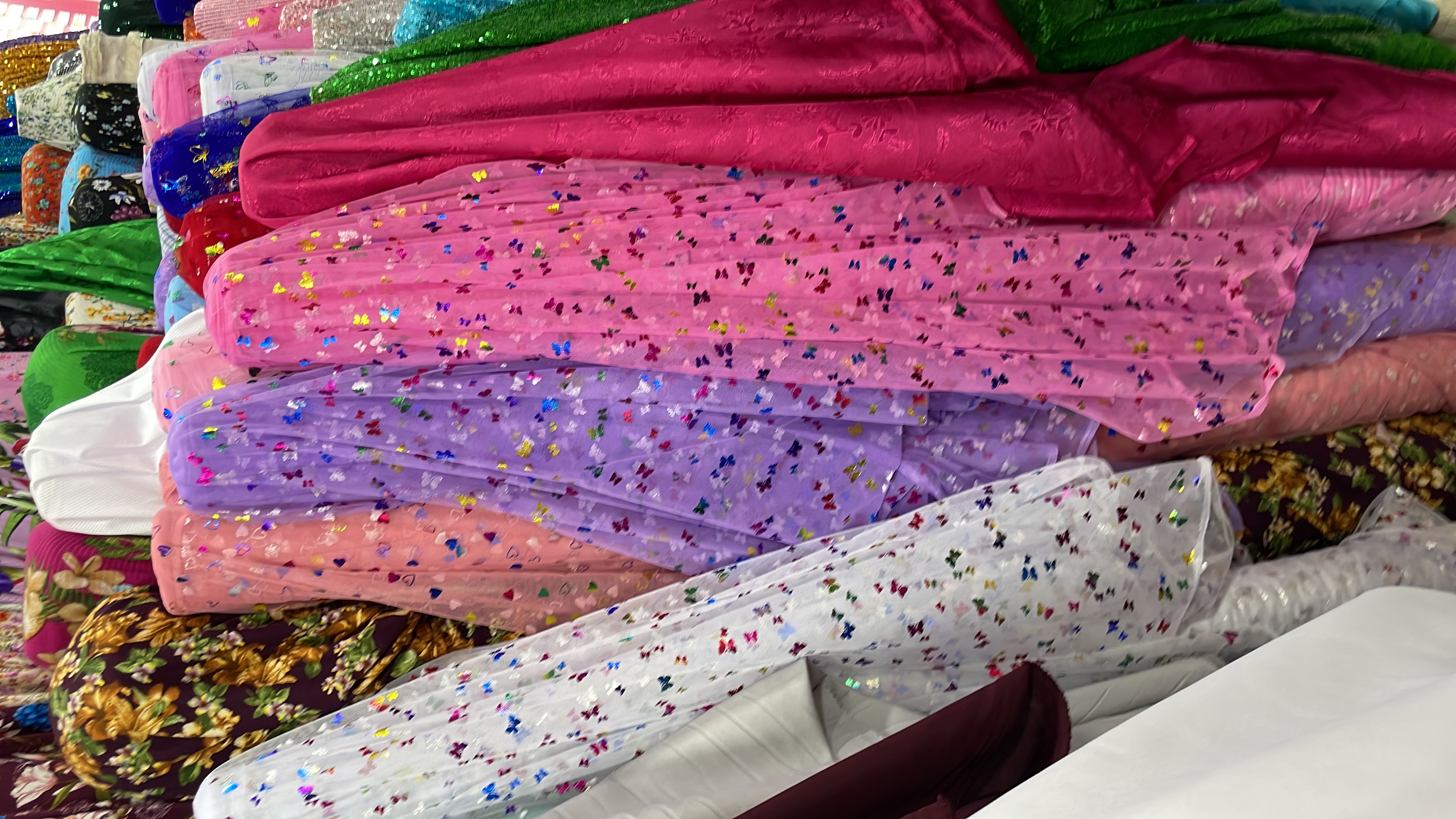 Tela de múltiples colores con estampados brillantes en una tienda.