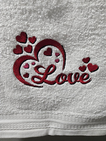 White hand towel with hearts and love embroidered on it