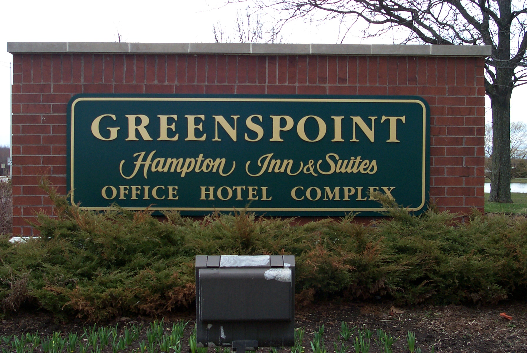 GOLD LETTERING ON GREEN BACKGROUND ON BRICK SIGN