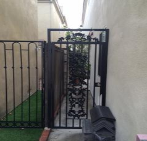 Wrought iron gate with lock in a side yard entry.