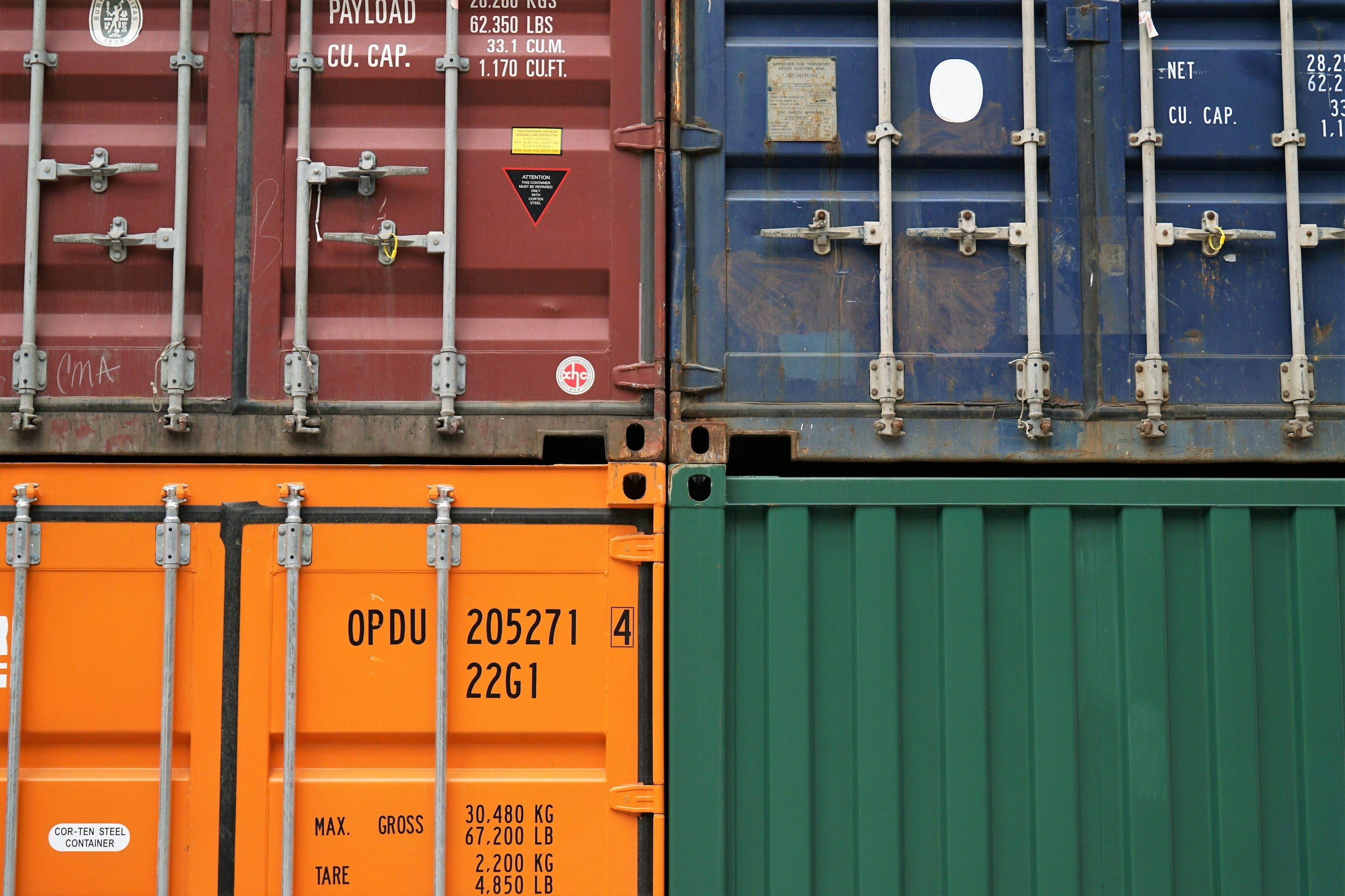 Close-up of stacked colorful shipping containers in red, blue, orange, and green. Close-up of stacked colorful shipping containers in red, blue, orange, and green.