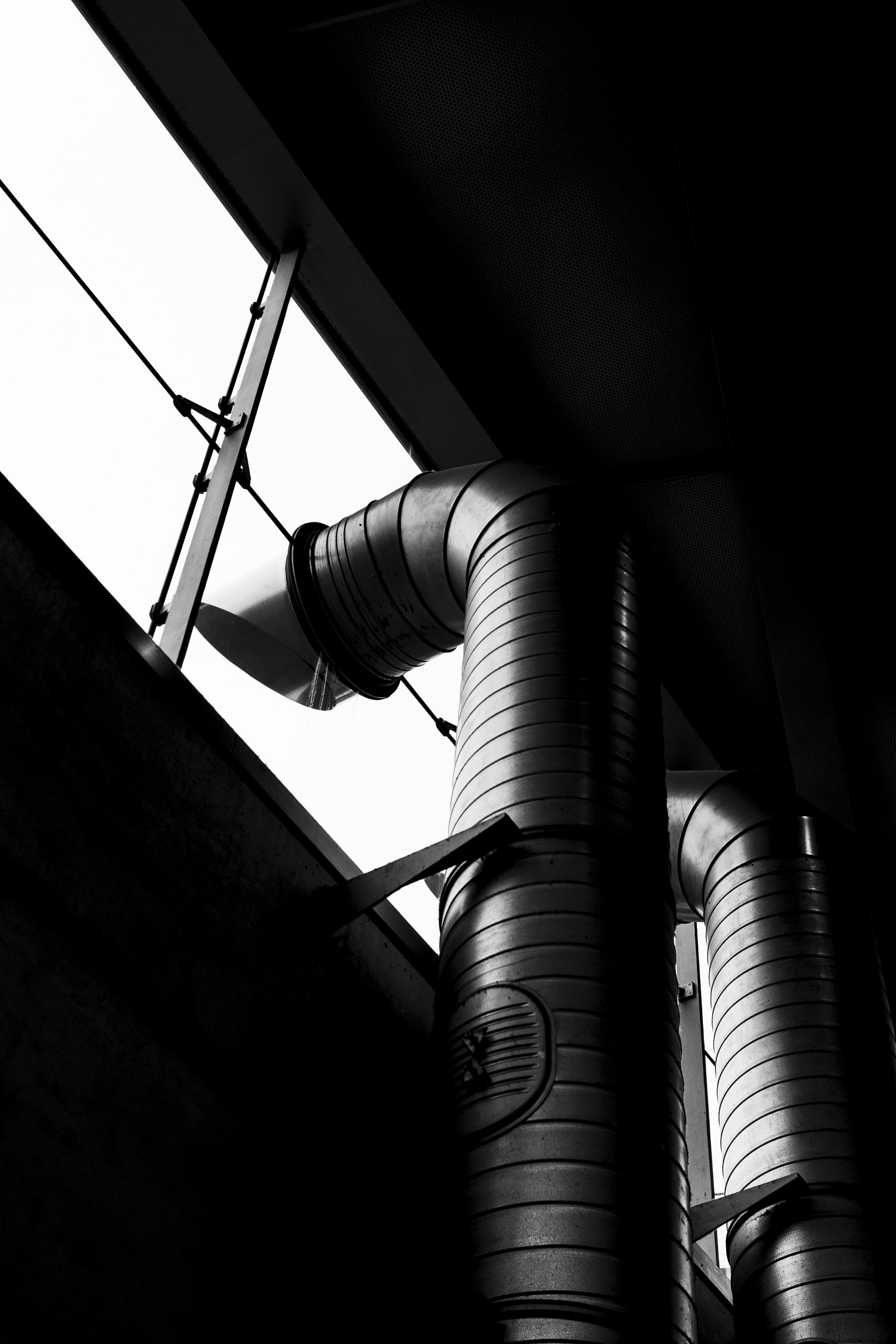 Ductos de ventilación metálicos en blanco y negro dentro de un edificio. Ductos de ventilación metálicos en blanco y negro dentro de un edificio.