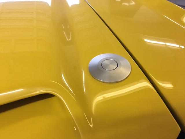 Low profile push button to unlatch the hood.