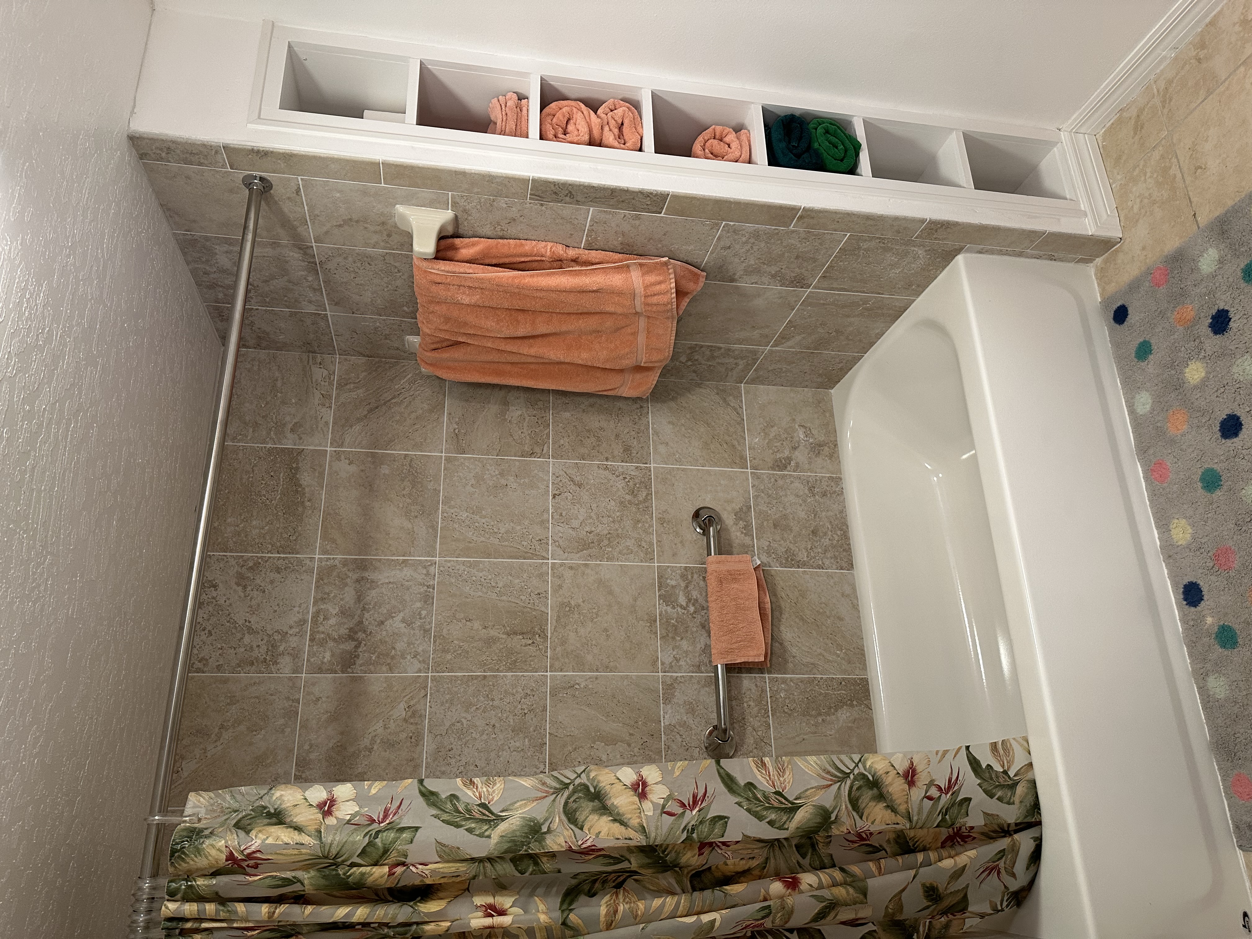 New tub-shower combo featuring 12x12 beige tiles and new grab bar.  Conveniently built-in cubby makes for easy storage of towels and bathroom items.