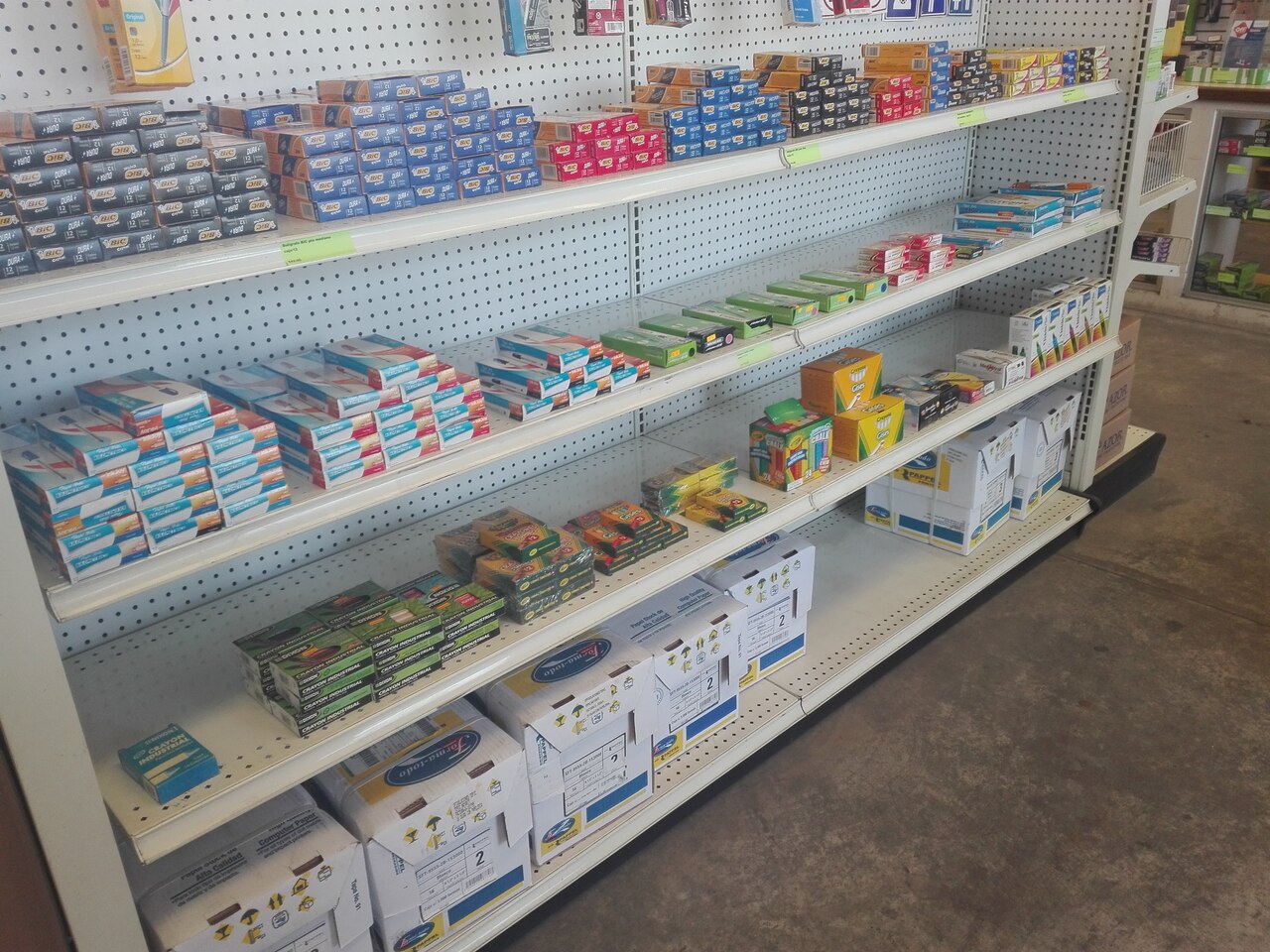 Estantes de tienda con cajas de ganchos y accesorios organizados en varios niveles.