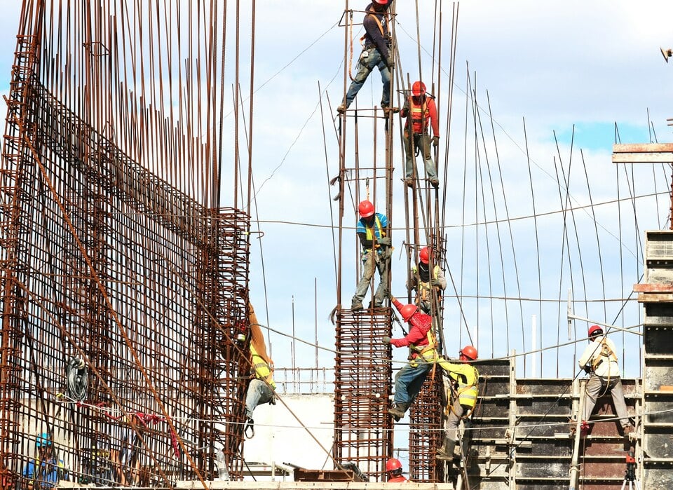 Trabajadores de la construcción con cascos en un sitio de obra, manejando estructuras de acero y cemento. Trabajadores de la construcción con cascos en un sitio de obra, manejando estructuras de acero y cemento.