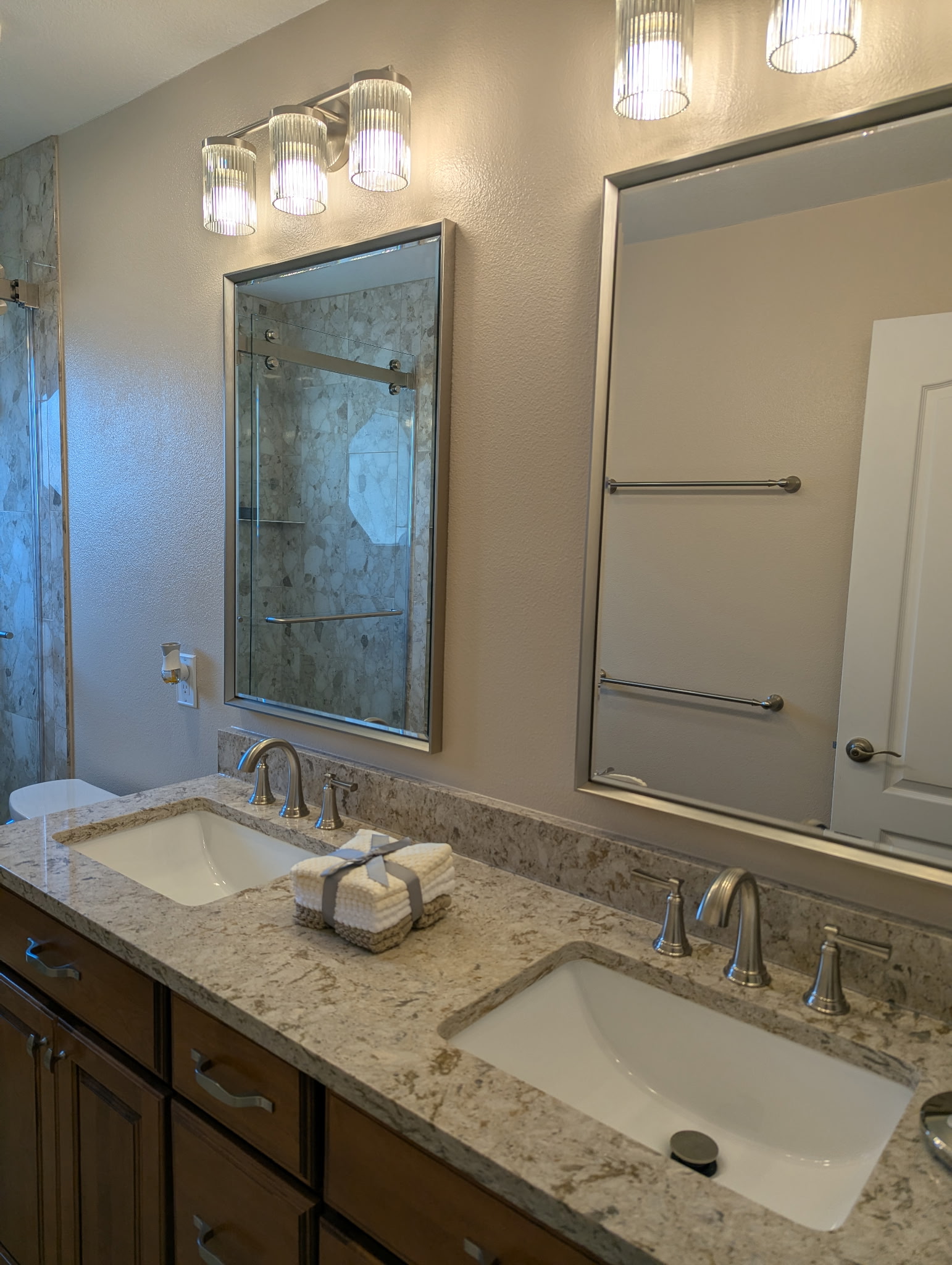 Double-sink vanity featuring stylish Cambria quartz with a matching backsplash, finished with brush nickel hardware and faucets for a clean, timeless look.
