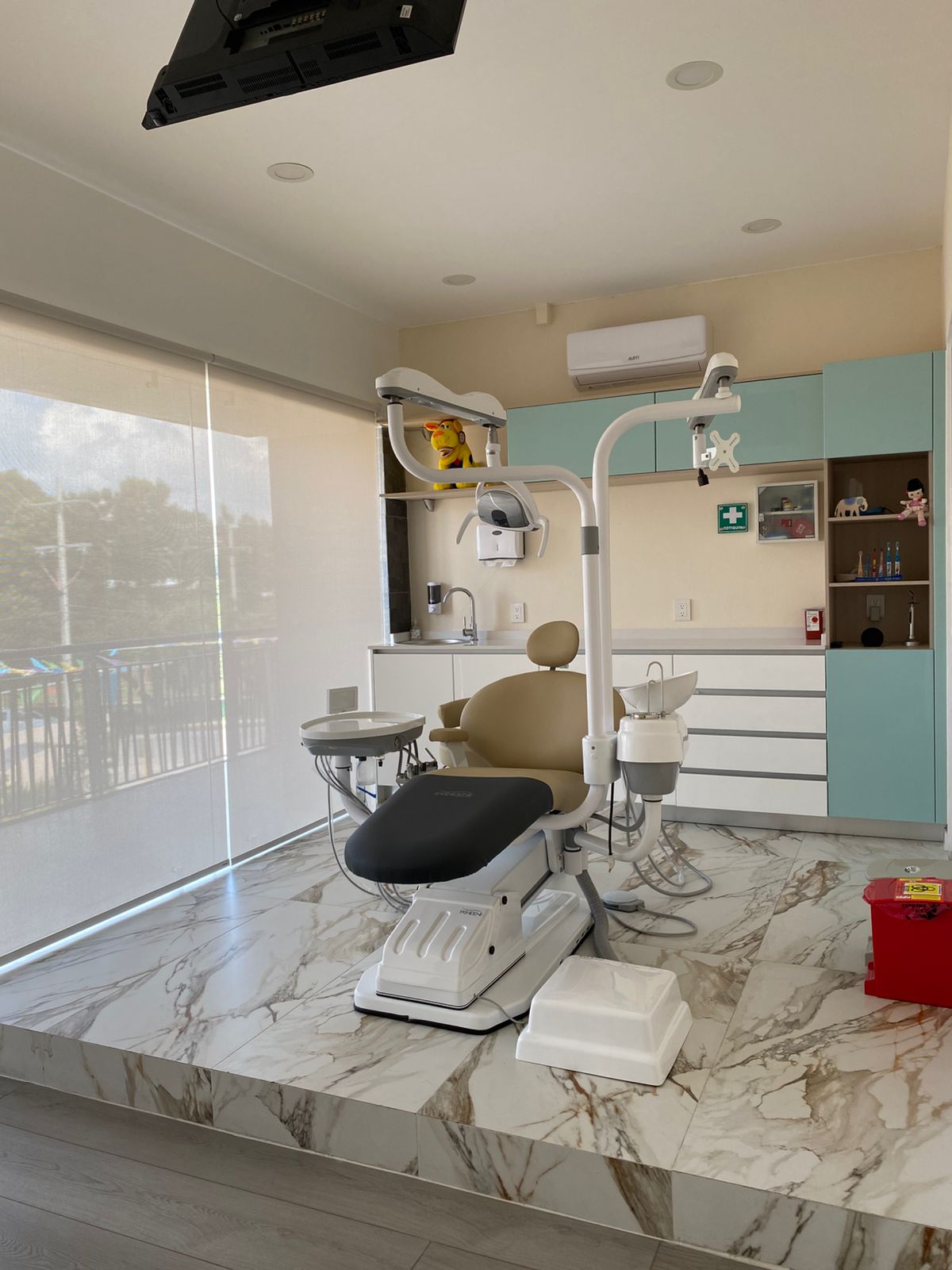 Consultorio dental moderno con silla de dentista, lámpara dental y muebles de almacenamiento en un entorno bien iluminado.