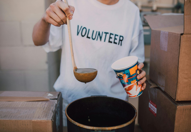 Someone serving food with a shirt that says Volunteer on it Someone serving food with a shirt that says Volunteer on it