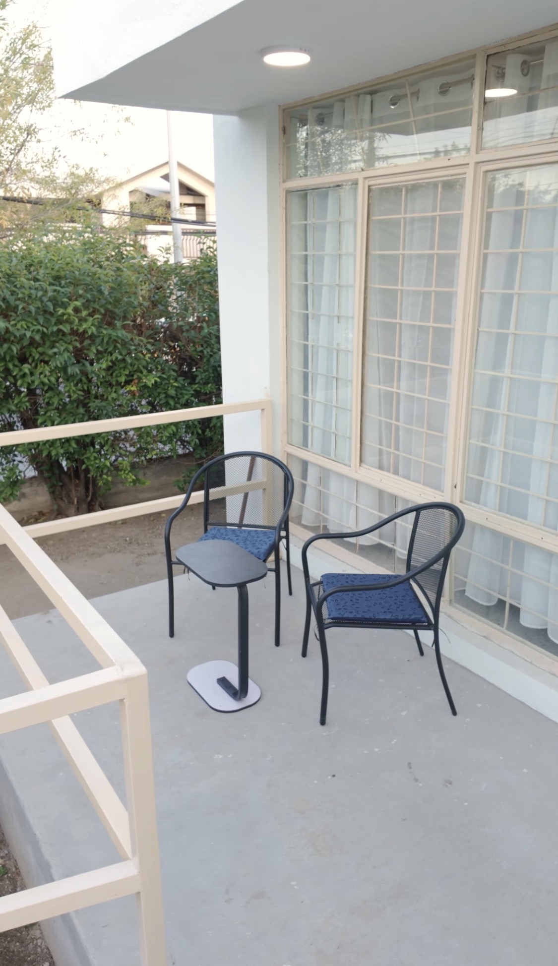 Pasillo luminoso con sofás, plantas y ventanas grandes.