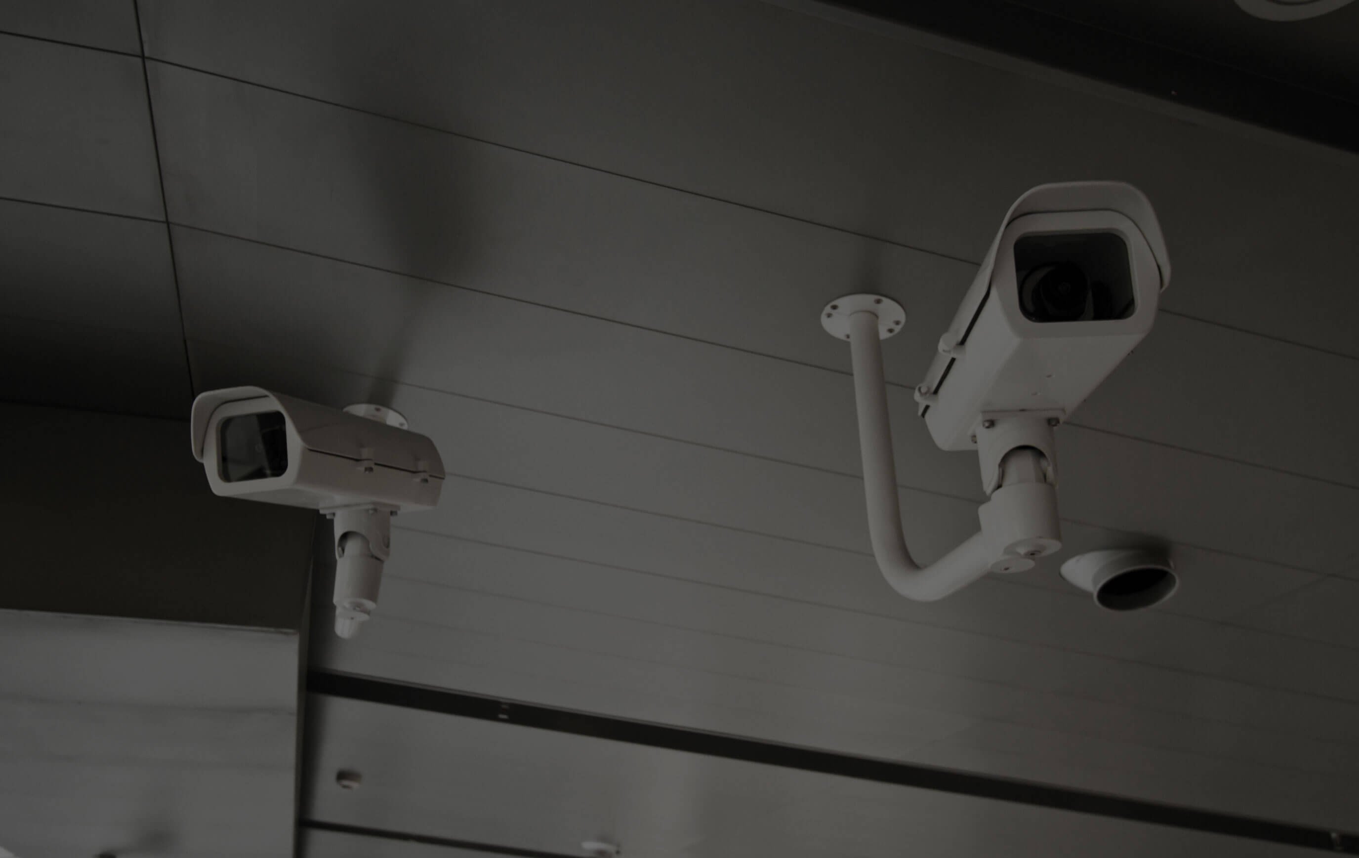 Dos cámaras de seguridad blancas montadas en el techo de un edificio.