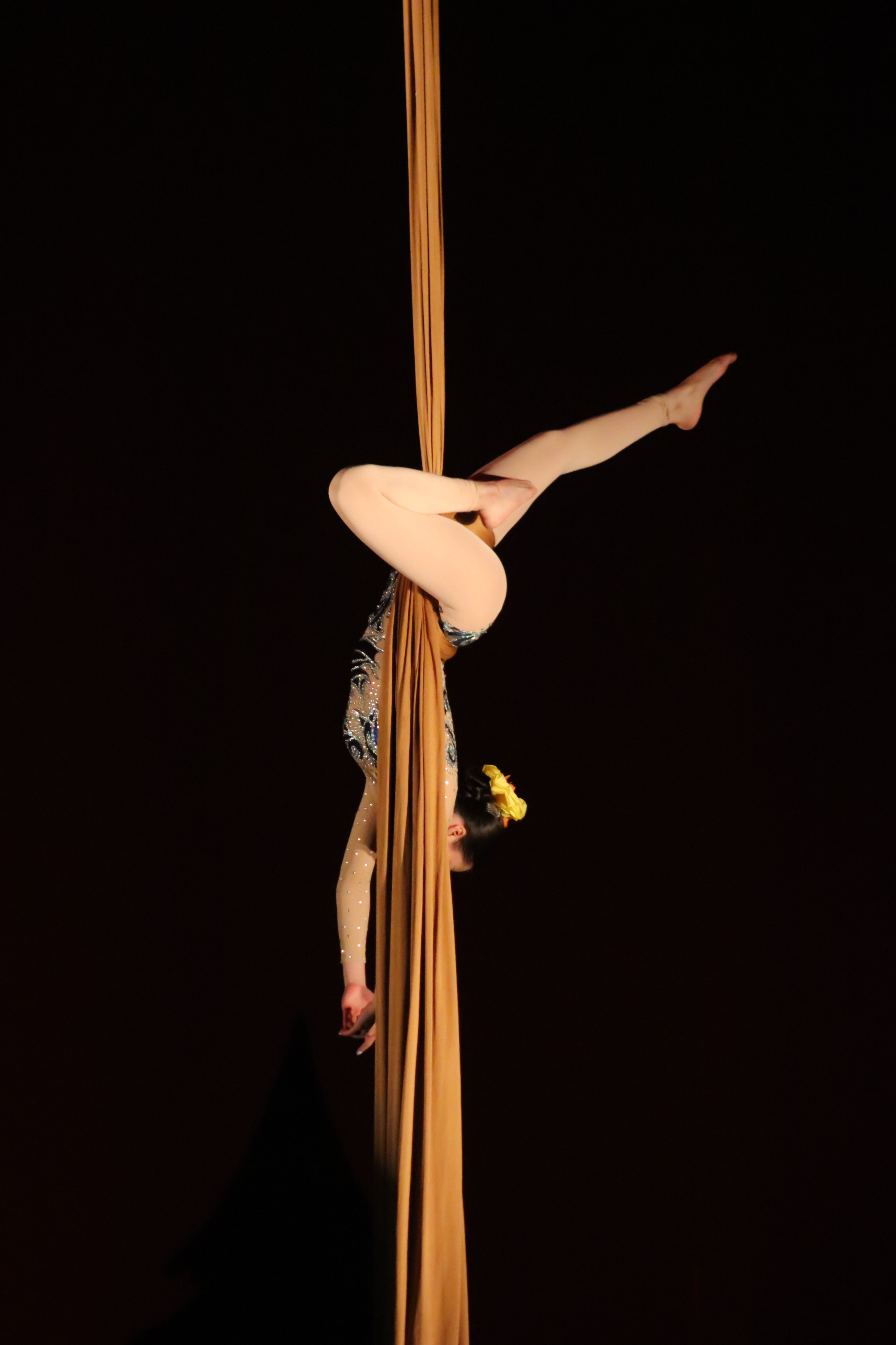 Bailarina en movimiento con mallas negras, saltando en un estudio de danza iluminado.