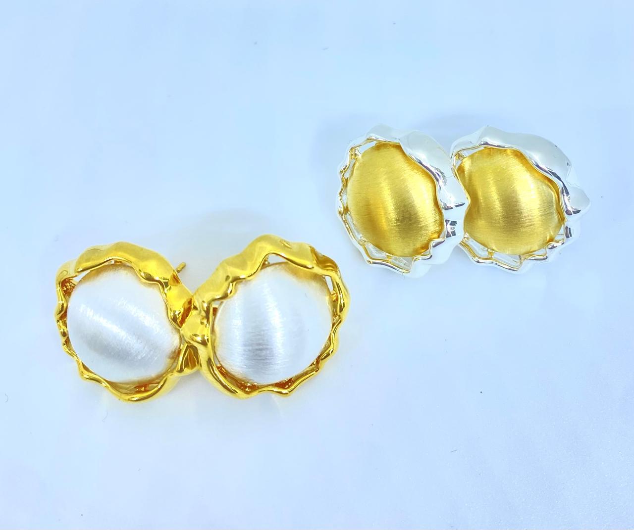 Pendientes redondos en metal dorado y plateado con diseño de borde ondulado sobre fondo blanco. Pendientes redondos en metal dorado y plateado con diseño de borde ondulado sobre fondo blanco.