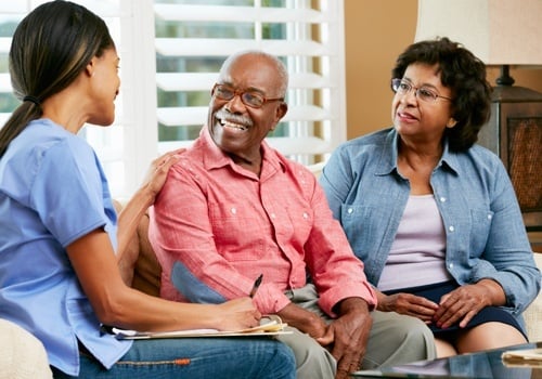 Nurse Making Notes During Home Visit With Senior Couple