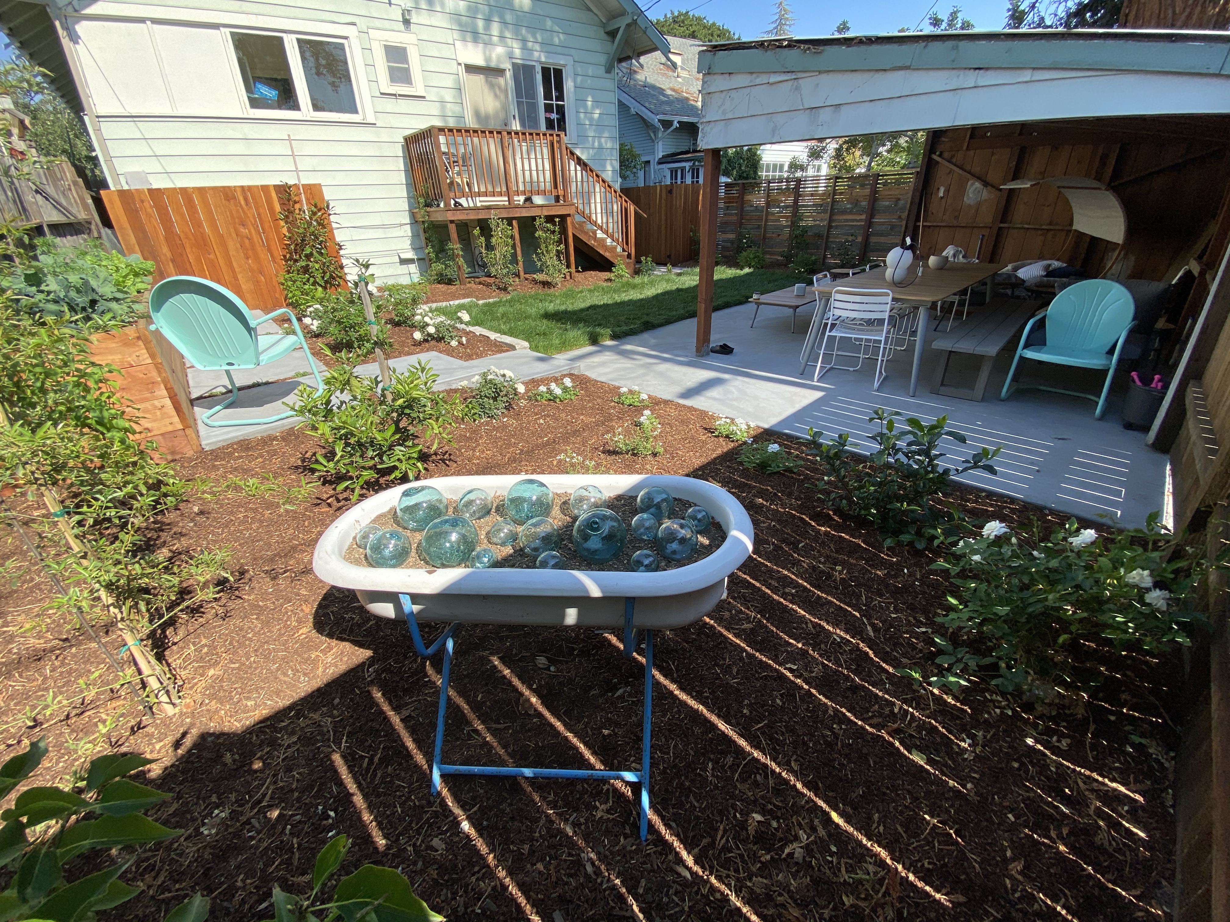After - antique bathtub with antique glass balls, opened up shed, poured patio, lawn & plantings