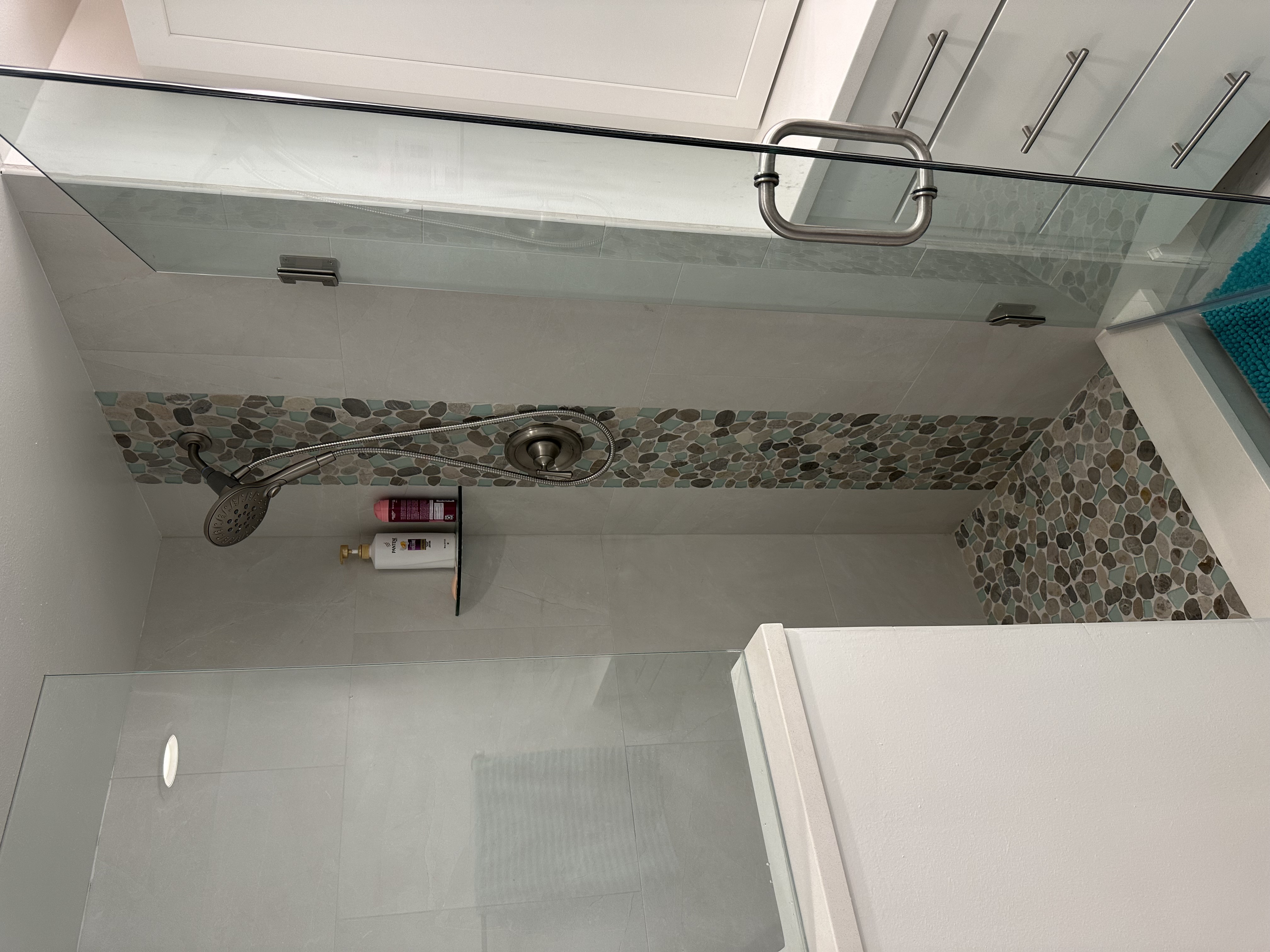 Gorgeous shower showcasing Oyster Bay shaved pebble waterfall with matching pebble shower floor.