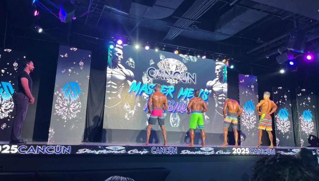 Competencia de fisicoculturismo Men’s Physique 2025 en Cancún con atletas musculosos en escenario iluminado Competencia de fisicoculturismo Men’s Physique 2025 en Cancún con atletas musculosos en escenario iluminado