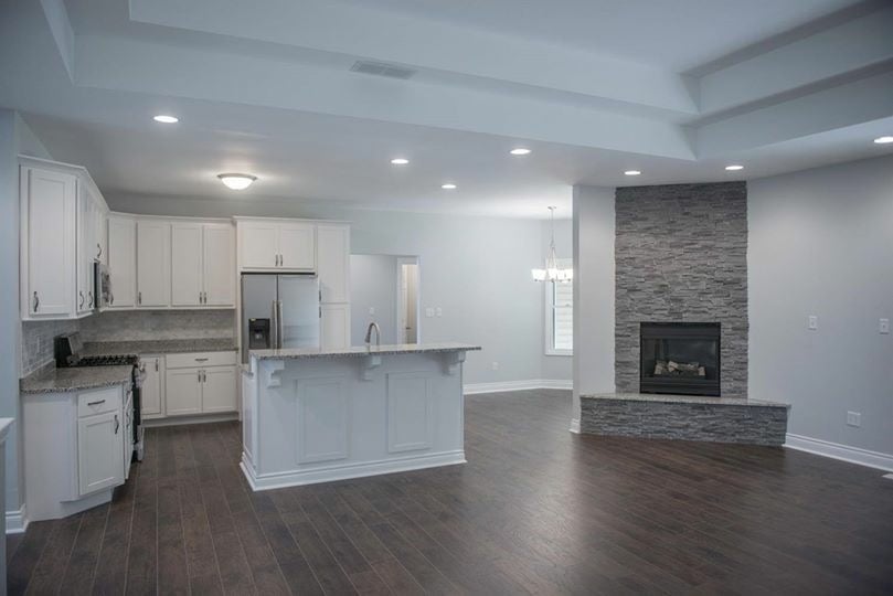 Hardwood floor installation in room with chimney and  kitchen.